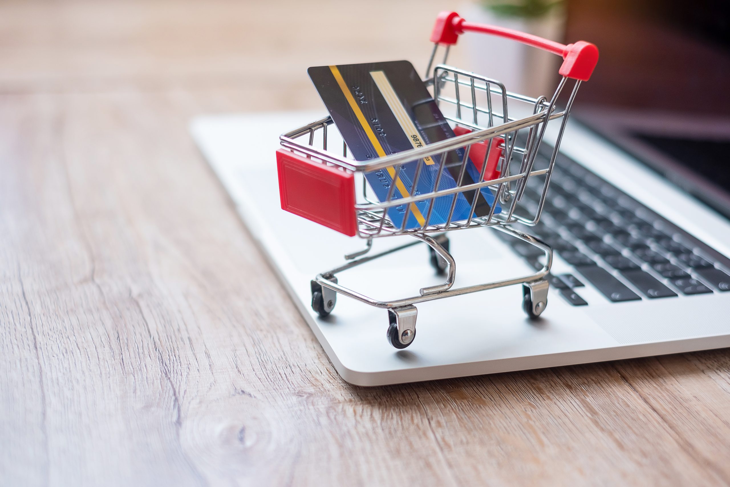 Shopping cart and credit card on laptop at home office.